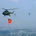 国旗を掲げて編隊飛行するヘリ