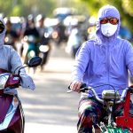 ハノイの猛暑の中、完全防備でバイクに乗る女性