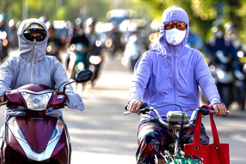 ハノイの猛暑の中、完全防備でバイクに乗る女性