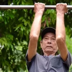 鉄棒で運動する高齢者