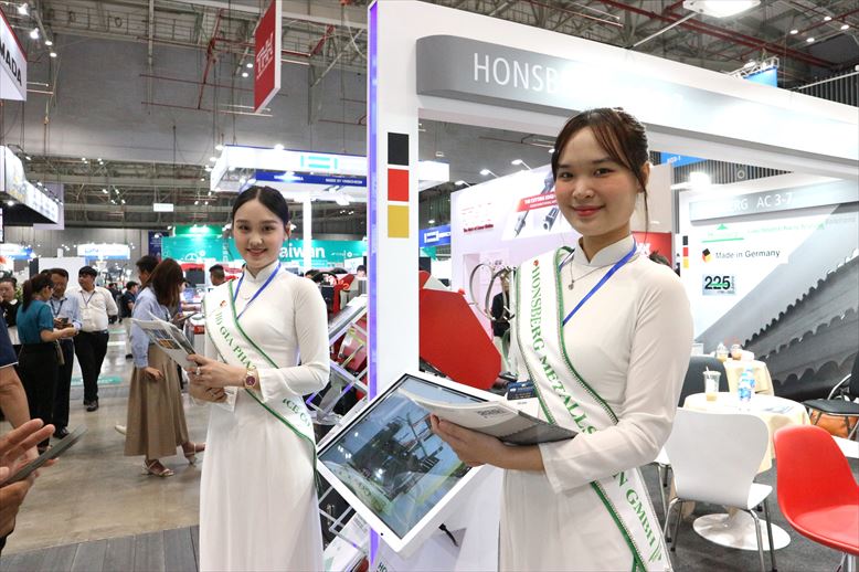 MTA VIETNAM 2025でパンフレットを配るコンパニオンの女性
