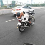 仰向けに寝転がってバイクを運転する男性