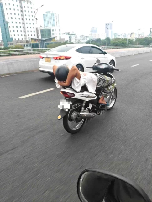 仰向けに寝転がってバイクを運転する男性
