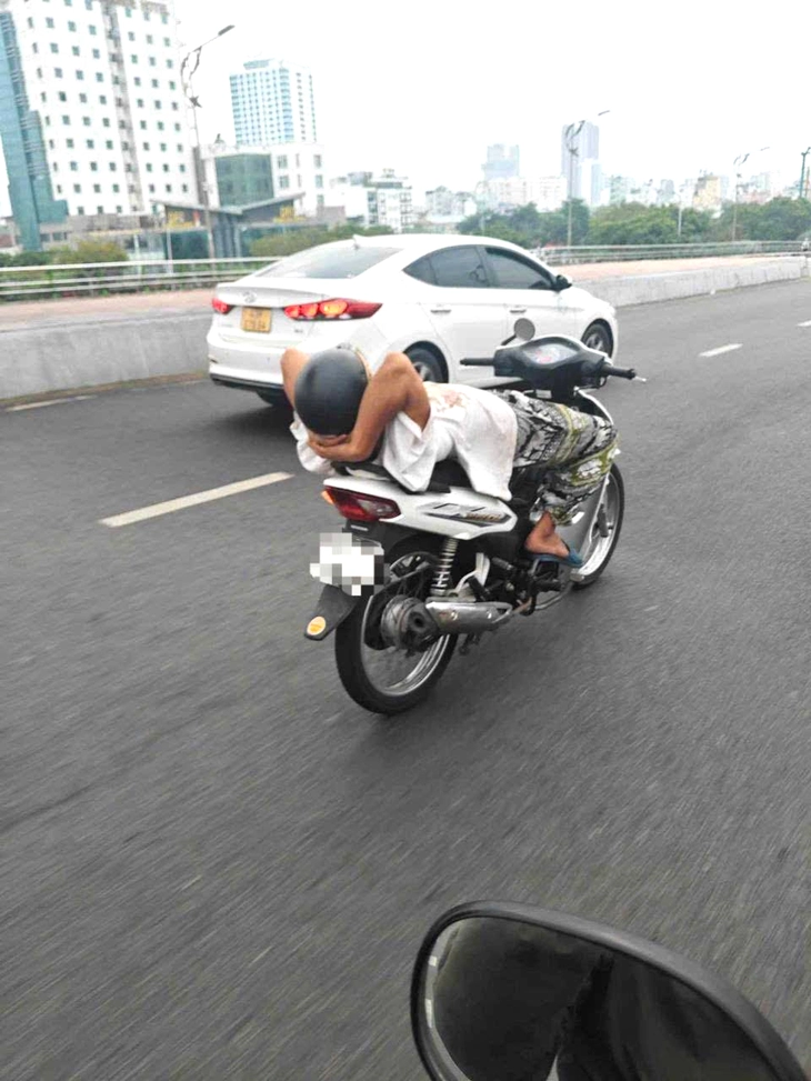 仰向けに寝転がってバイクを運転する男性