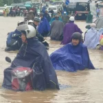豪雨で浸水した道路を進む人々