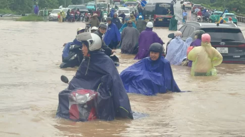 豪雨で浸水した道路を進む人々