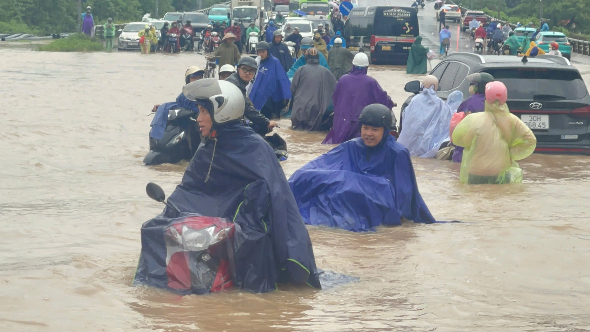 豪雨で浸水した道路を進む人々