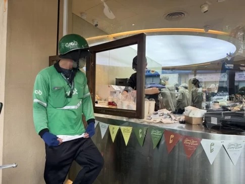 飲食店の外で立って待つ配達員