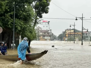 冠水した道路を船で移動するフエの市民