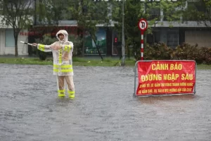 冠水したハノイ市内で交通誘導する警察官