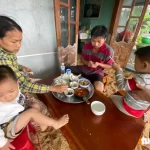 洪水の被害を受けた村で食事をとる家族