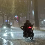 大雨のホーチミン市内を走るバイク