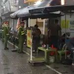 ハノイ市内で雨天でも歩道占拠を取り締まる警察官