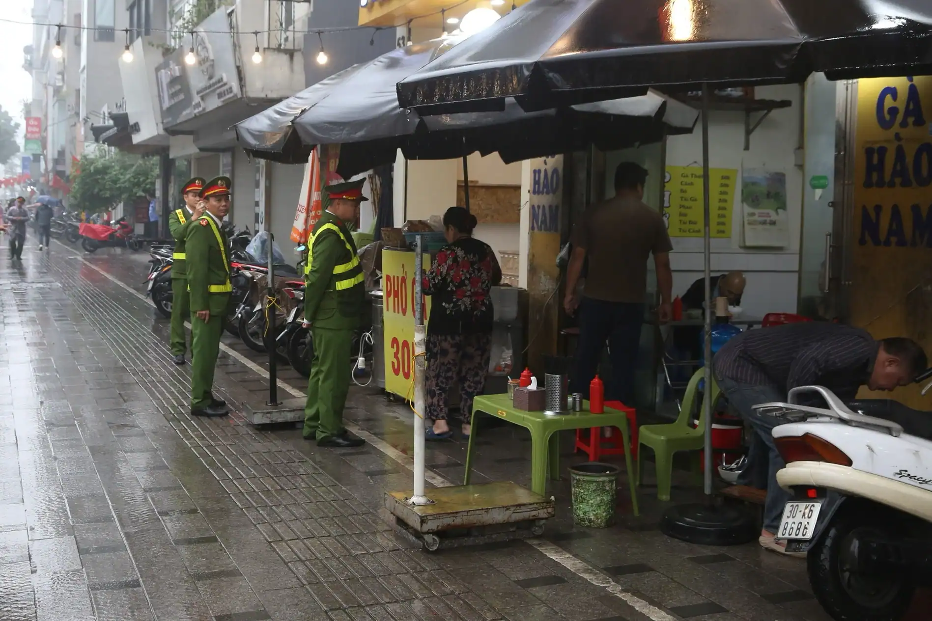 ハノイ市内で雨天でも歩道占拠を取り締まる警察官