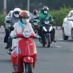 ホーチミン市の早朝の気温低下により厚着をしてバイクに乗る市民