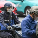 厳しい寒さに見舞われたベトナム北部で防寒具を着てバイクに乗る市民