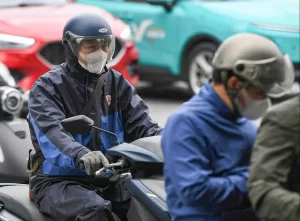 厳しい寒さに見舞われたベトナム北部で防寒具を着てバイクに乗る市民
