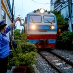 通過する列車に合図を送る踏切番の女性