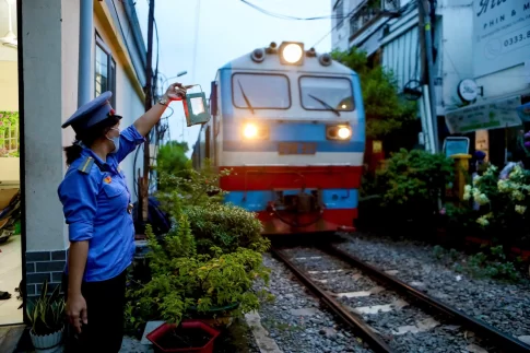 通過する列車に合図を送る踏切番の女性