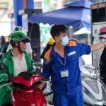 ホーチミン市内のガソリンスタンドでバイクの給油を受ける市民
