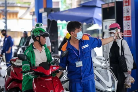 ホーチミン市内のガソリンスタンドでバイクの給油を受ける市民