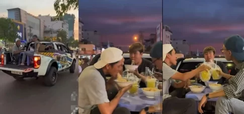 ホーチミン市の道路上で走行するピックアップトラックの荷台で食事する若者たち