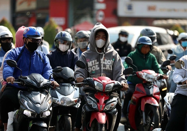 強烈な日差しを避けてバイクに乗るホーチミン市民