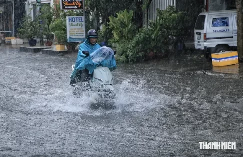 ホーチミン市内の冠水した道路を走るバイク
