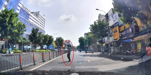 横断歩道のない場所で道路を渡ろうとするホーチミン市内の歩行者