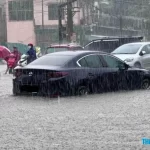 大雨で道路が冠水し、タイヤまで水につかる自動車