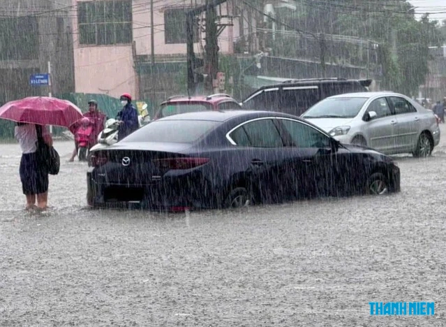 大雨で道路が冠水し、タイヤまで水につかる自動車