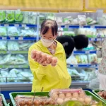 スーパーで卵の価格を確認するベトナム人消費者