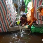 大雨で浸水した家屋から水を汲みだす女性