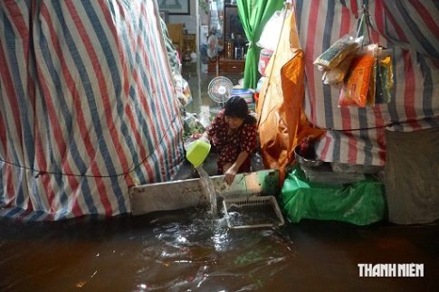 大雨で浸水した家屋から水を汲みだす女性